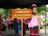 Une fille tient le panneau avec le nom du village